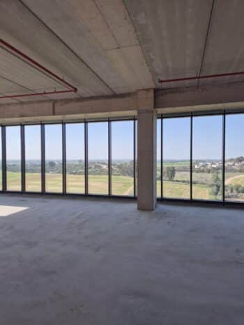 היחידה נמצאת בקומה גבוהה בבניין עם חלונות מסך שמשקיפים לשדות